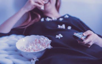 woman watching tv eating popcorn