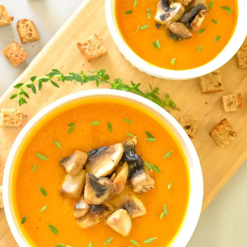 two bowls of vegan carrot and curry cream soup overhead shot