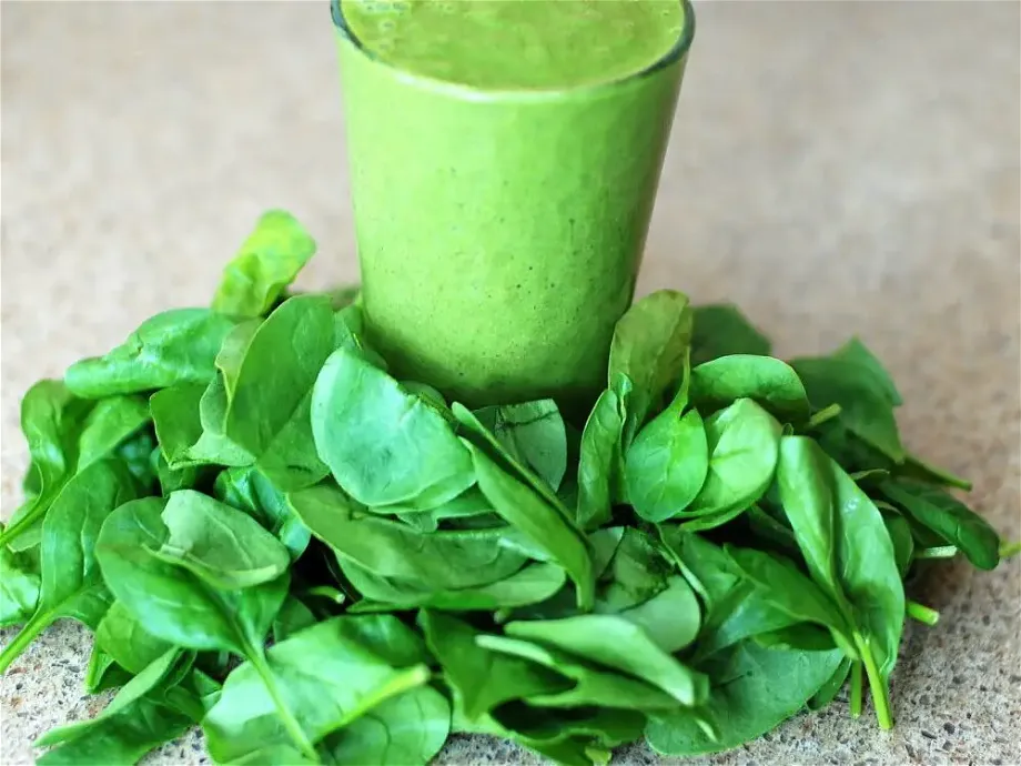 ¾ shot of green smoothie and spinach leaves