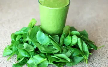 ¾ shot of green smoothie and spinach leaves