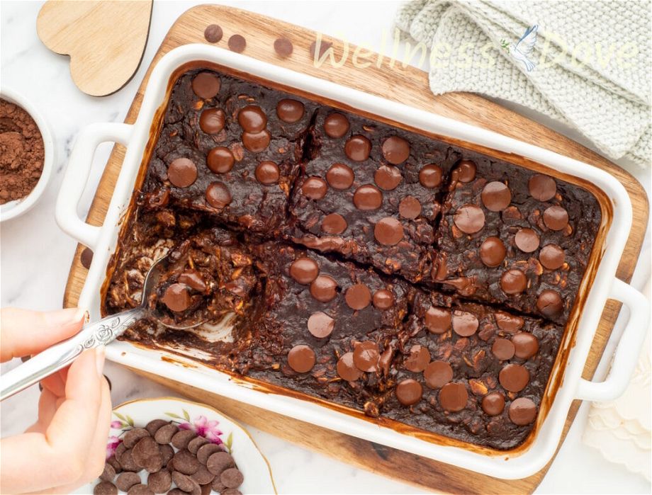 overhead view of the Vegan Brownie Baked Oatmeal, a piece is missing and a spoon is taking some of the brownie out.