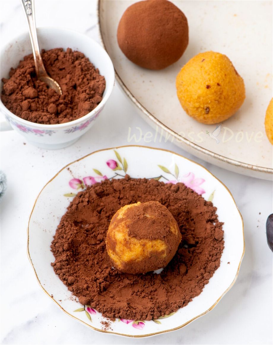 one of the vegan sweet potato vegan truffles in a small plate, half-rolled in cacao