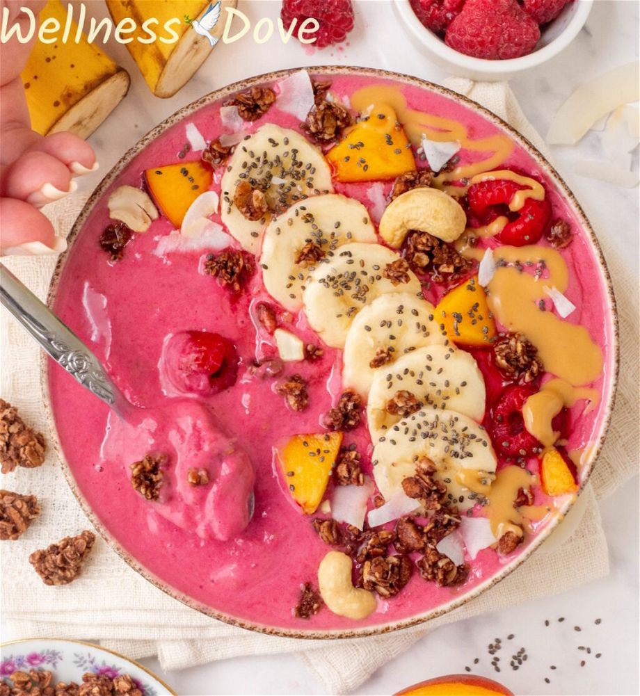 an overhead shot of the Raspberry Banana Vegan Smoothie Bowl while a hand is taking some out with a spoon