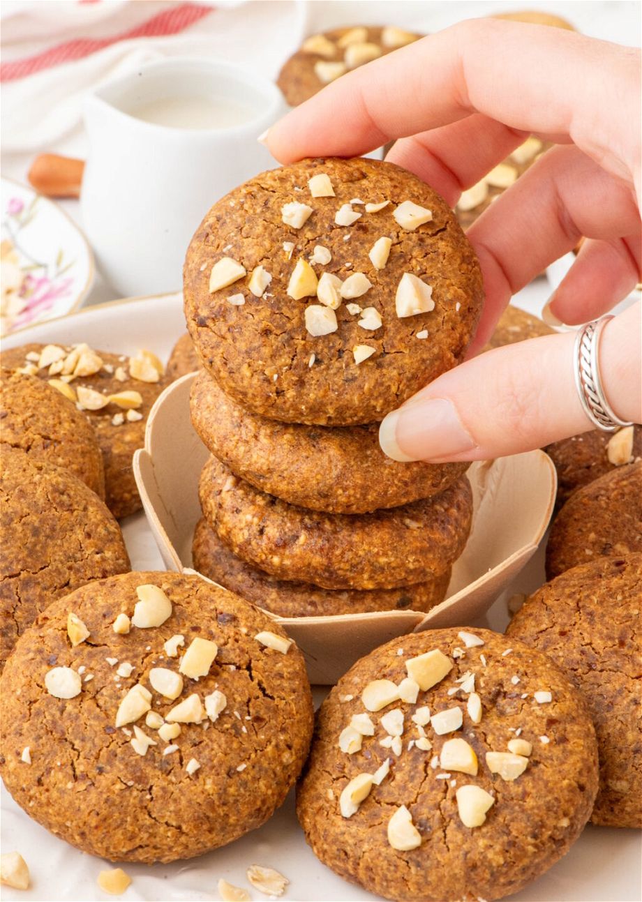 the Oatmeal Peanut Butter Vegan Cookies on top of each other and a hand is holding one