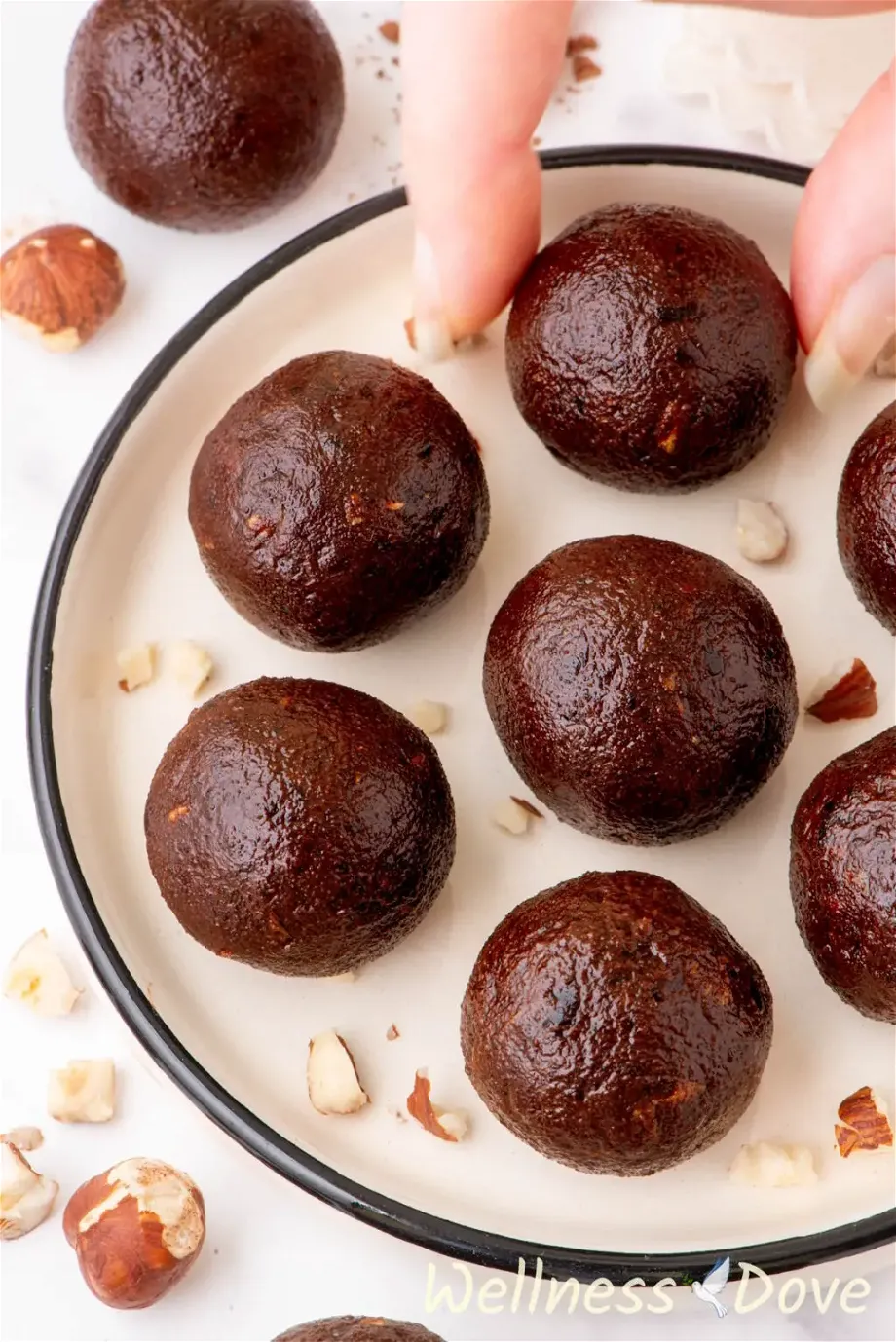 an overhead shot of the Healthy 3-Ingredient Vegan Energy Balls while a hand is taking one of them out