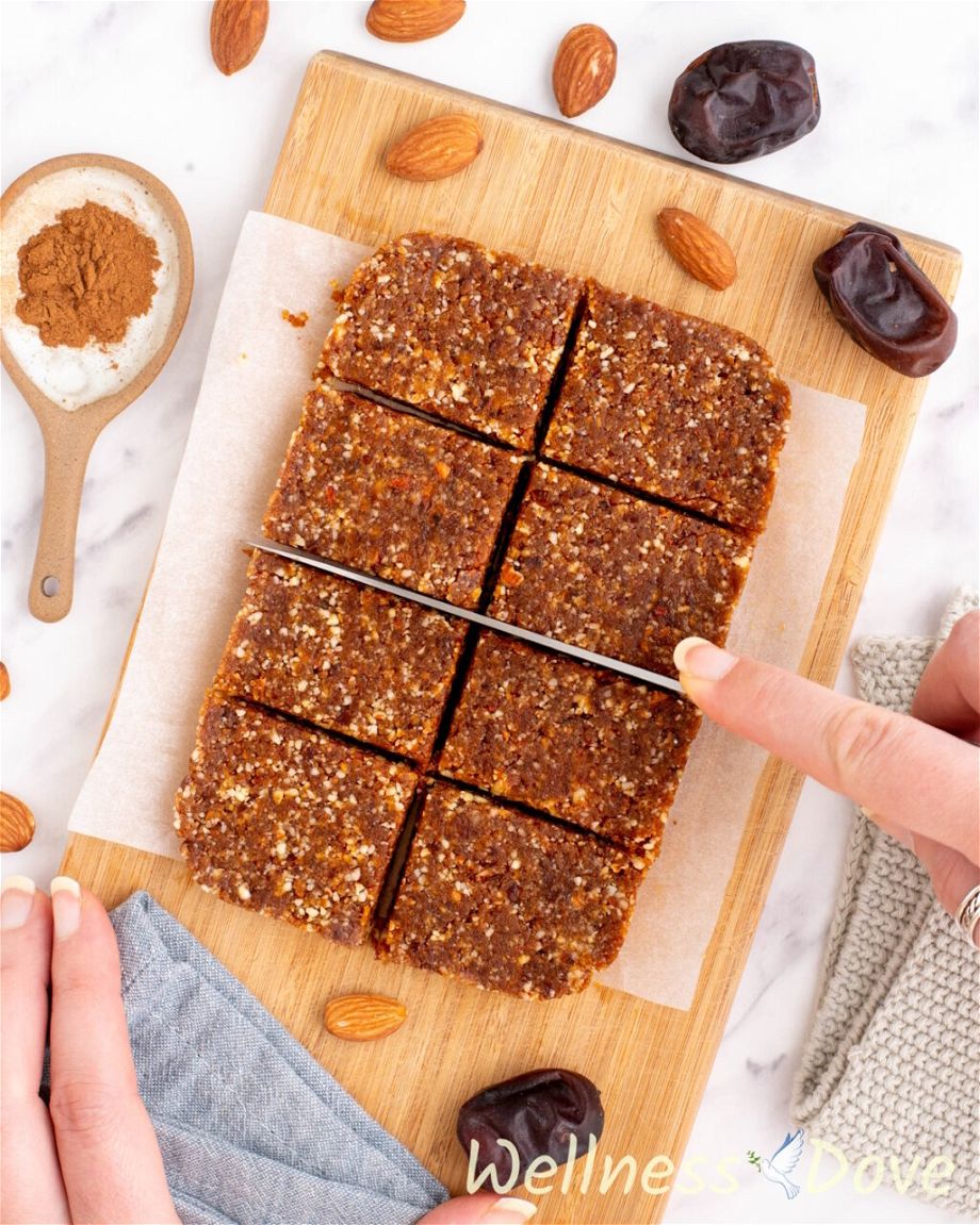 the Almond Peanut Butter Bars from above, a hand with a knife is cutting them