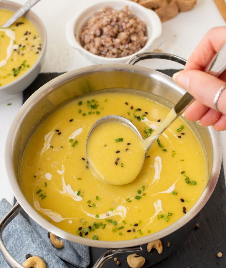 a hand taking some of the soup with a ladle from a pot