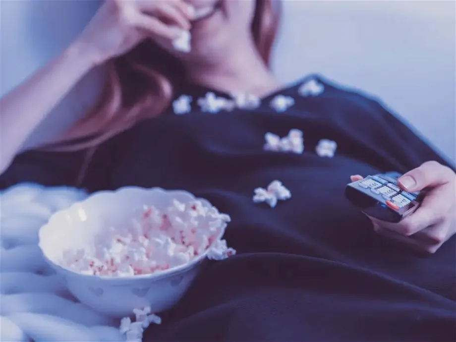 woman watching tv eating popcorn