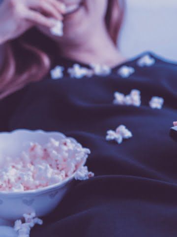 woman watching tv eating popcorn