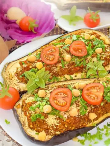 Hearty and tasty Chickpea and Tomato Stuffed Eggplant recipe! Full of flavor and fresh seasonal vegetables, you are going to love this recipe. It is 100% vegan, prepared with only whole plant-food ingredients. Super delicious filling with a chewy texture from the mashed chickpeas!