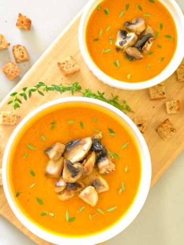 two bowls of vegan carrot and curry cream soup overhead shot