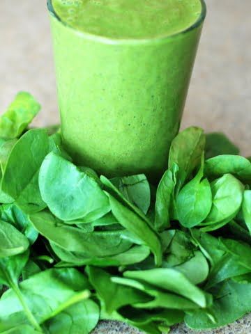 ¾ shot of green smoothie and spinach leaves