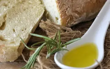 ¾ view of a spoon of olive oil and sliced white bread