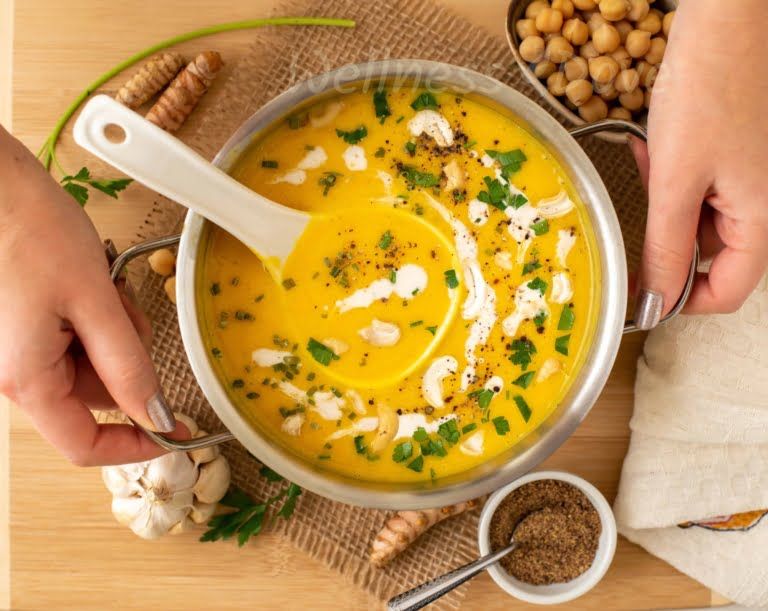 Two hands serving the soup on a table