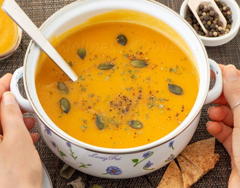 two hands holding a pot with parsnip vegan soup