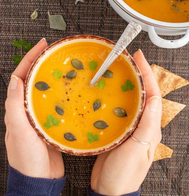 two hands holding a bowl of vegan parsnip soup