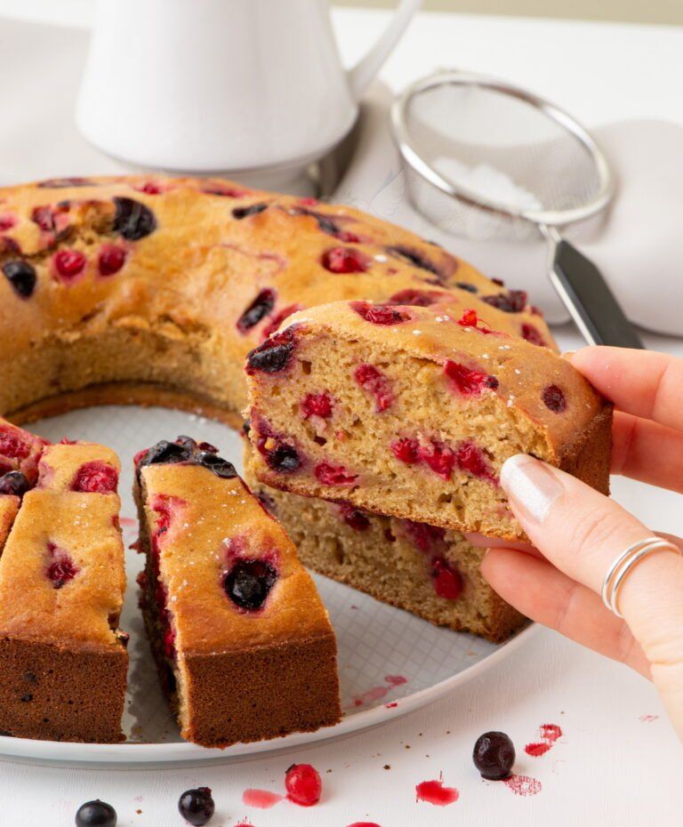 a hand holding a piece of the bundt cake