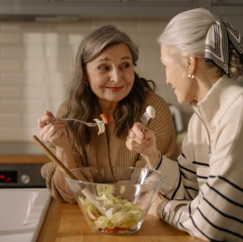 two mature women eating salad