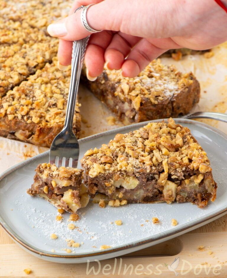 a piece of the vegan apple pie in a plate. A person takes a small bite with a fork.