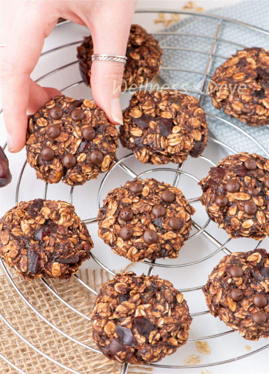 the vegan banana oatmeal breakfast cookies  on a metal rack and a hand is taking one of them