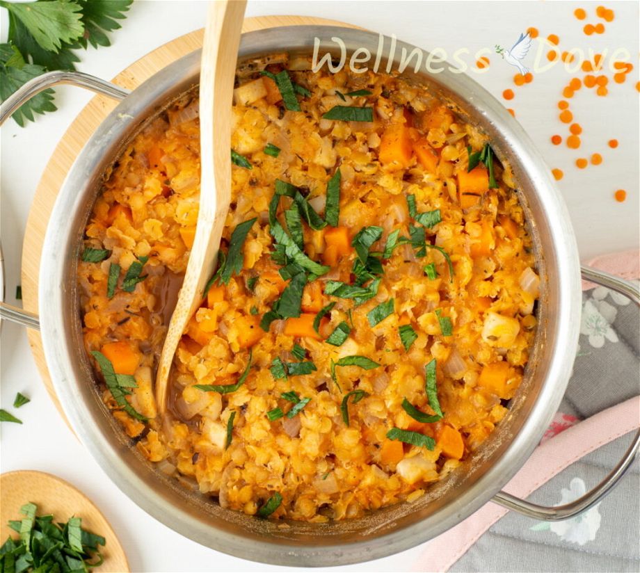 the easy red lentils vegan soup in a pot with a wooden spoon inside