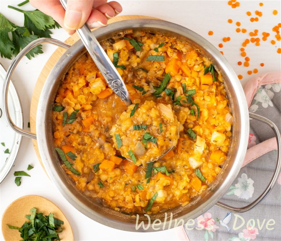 the easy red lentils vegan soup in a pot with a metal ladle taking some out