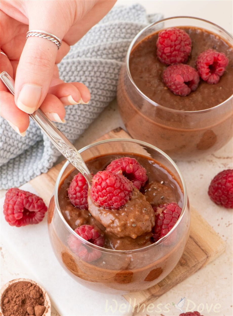 3 cups of easy vegan chocolate chia seeds pudding and a hand taking some of it with s spoon