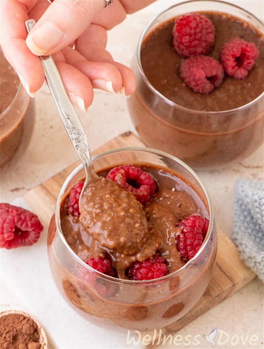 a 3/4 view of a hand taking some of the easy vegan chocolate chia seeds pudding with a spoon