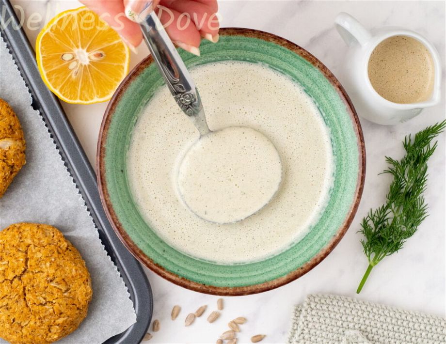 the the easy vegan sunflower seeds sauce  in a green bowl with a ladle inside