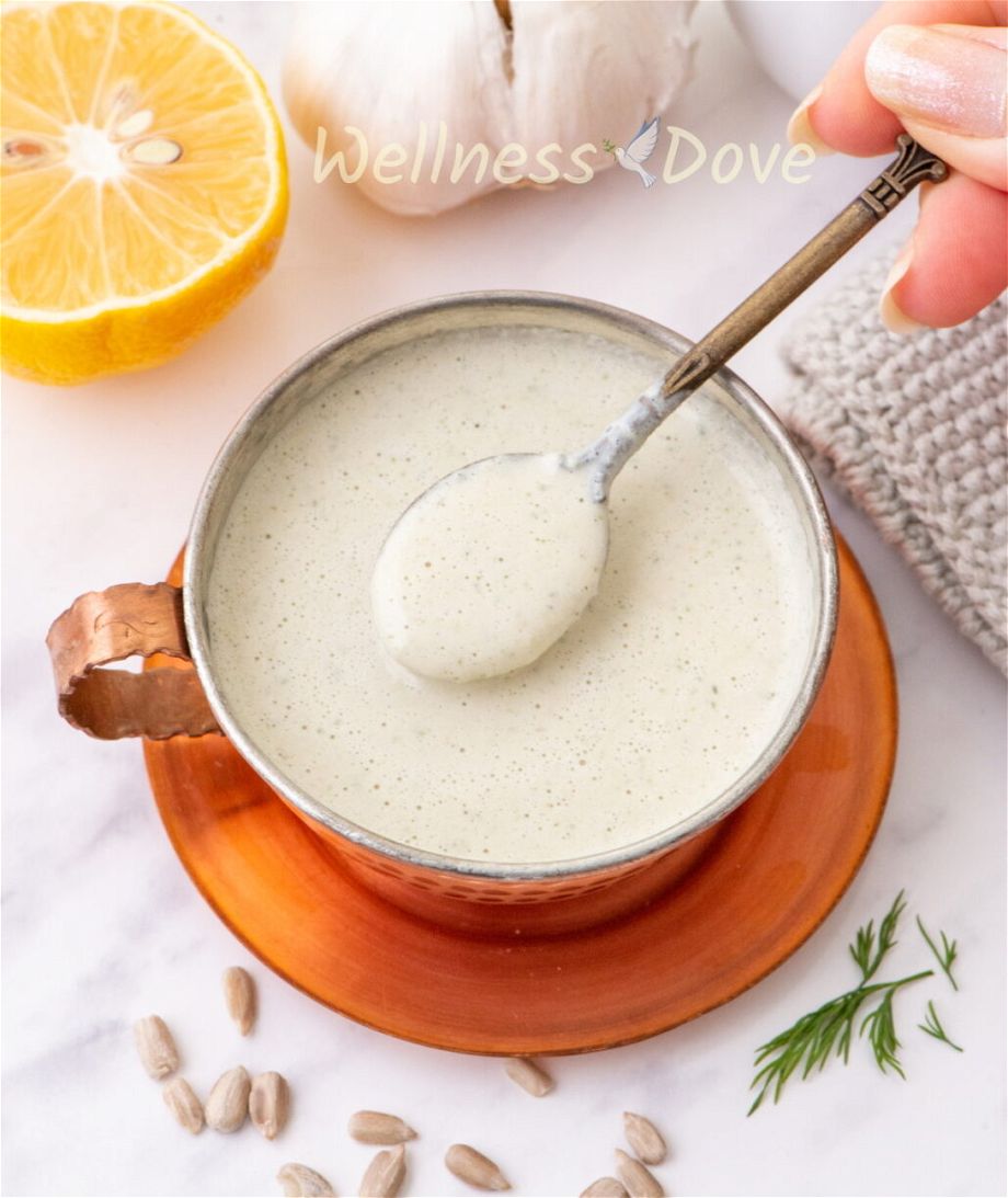 easy sunflower seeds sauce in a copper cup, with a hand taking a spoonfull of the sauce