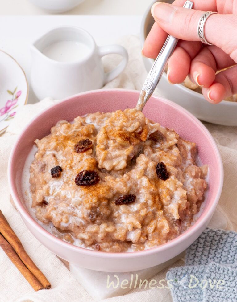 the quick vegan brown rice pudding in a purple bowl and a hand is taking some of it out