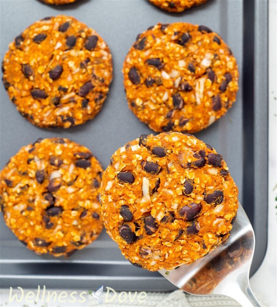 an overhead shot of the Sweet Potato Black Bean Burgers, one is being taken away with a spatula.