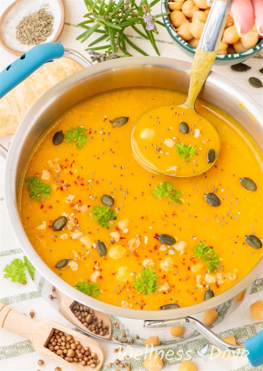 the Squash & Parsnip Vegan Soup in a pot while somebody is taking some of it out with a laddle